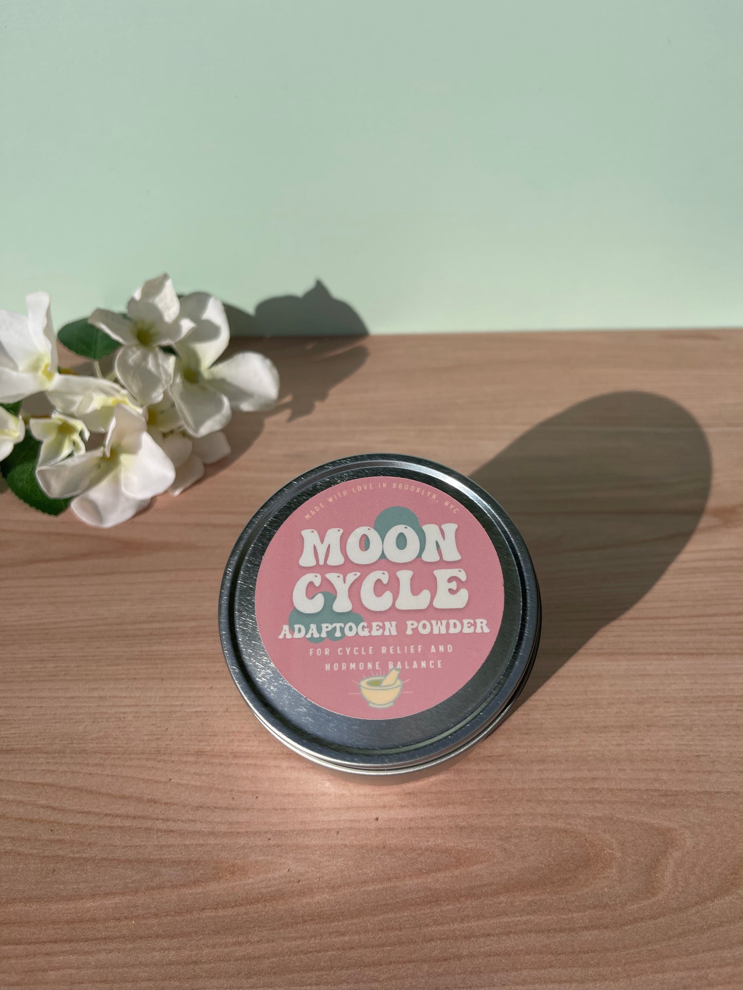 metal tin labeled moon cycle sitting on wood counter next to flowers