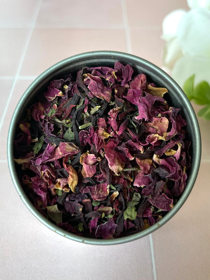 metal tin sitting on tile counter filled with a blend of herbs next to flowers